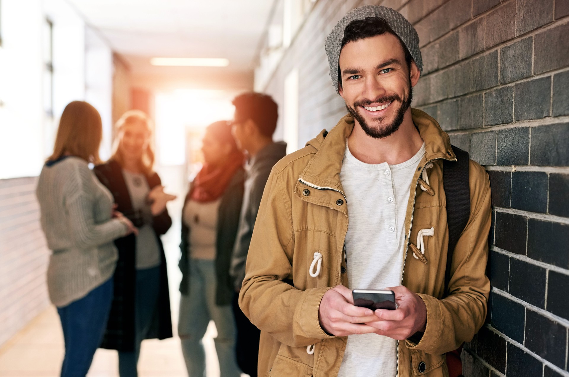 Hallway, portrait and happy man with smartphone in university for learning application or higher education. Social media, smile or student texting on internet for academic registration or scholarship